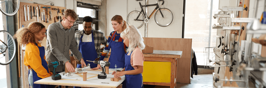 Multi-Cultural Team In Workshop Assembling Hand Built Sustainable Bamboo Bicycle Frame