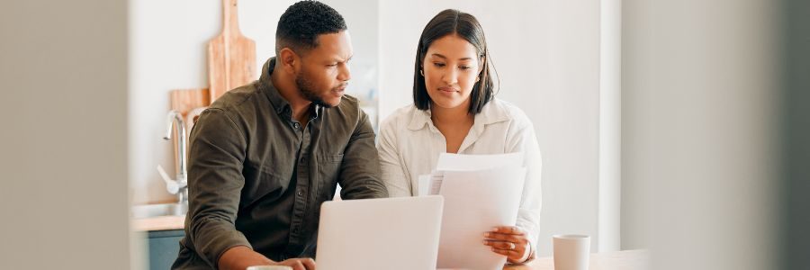 couple-with-laptop-looking-at-document-paper-work-caveat-loans-tiger-finance