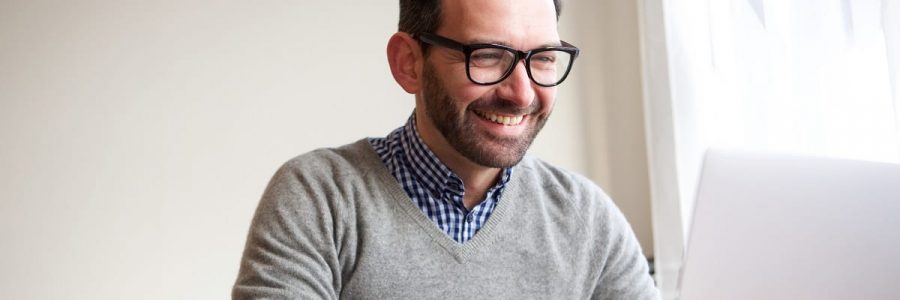 Portrait of happy businessman working with laptop computer